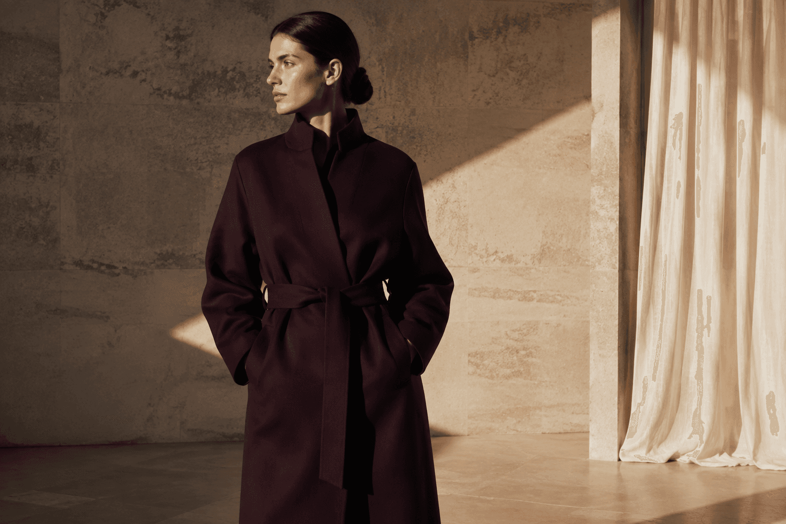 Model in an aubergine coat in warm architectural light